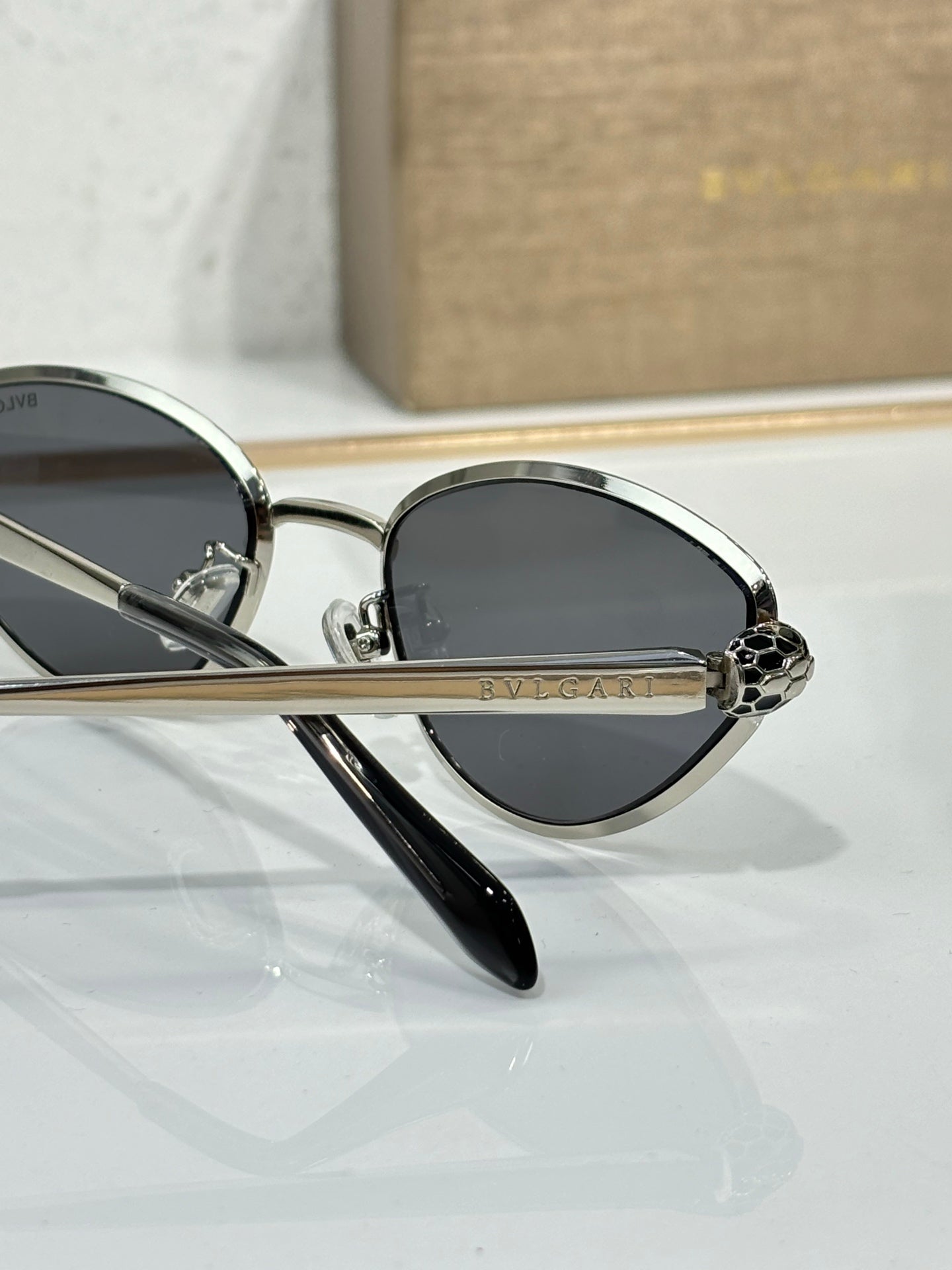 Bvlgari glasses close-up with dark lenses, gold-tone frame, and logo detail