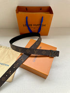 Monogram belt with gold-tone LV buckle on dark canvas strap with black leather edge.