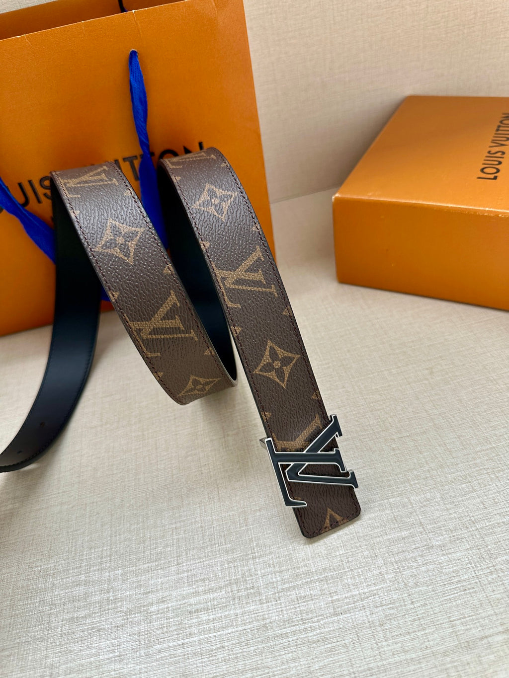 Monogram belt strap with gold-tone LV buckle and dark brown canvas finish.