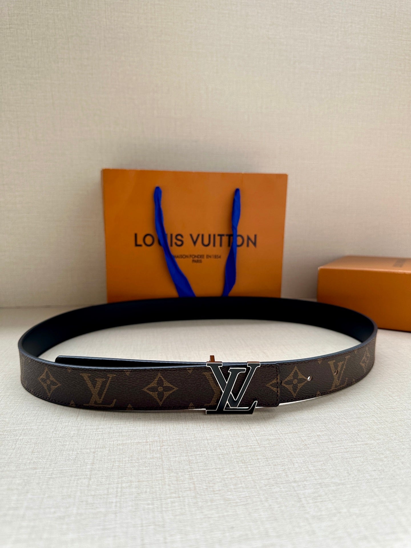 Louis Vuitton belt, dark monogram canvas with gold-tone LV buckle and black trim.