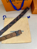Louis Vuitton monogram belt strap with gold-tone LV buckle on cream pouch