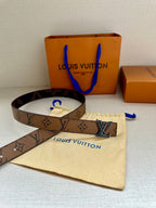 Louis Vuitton monogram belt with gold-tone LV buckle on cream dust bag