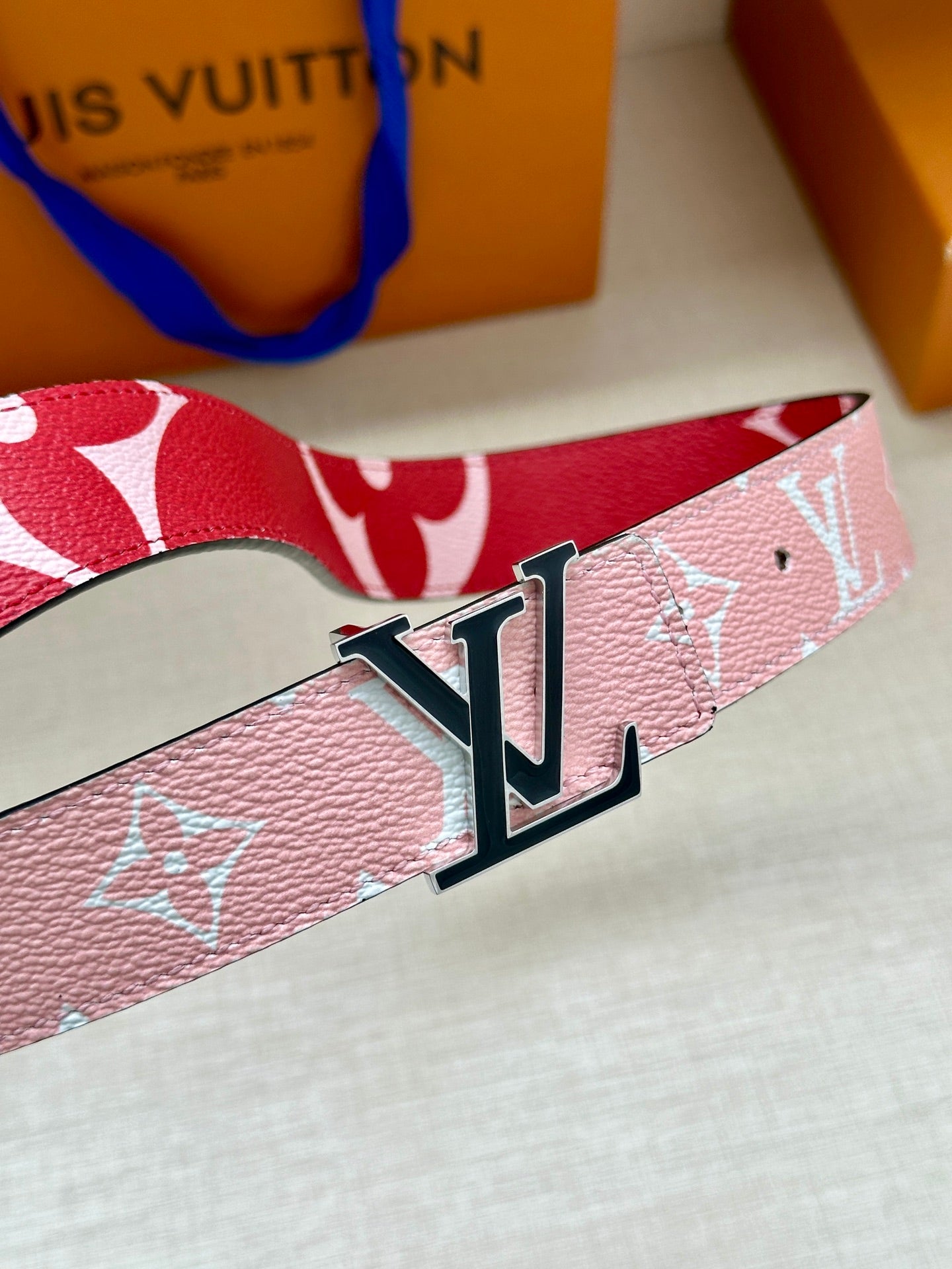 Pink monogram belt with large silver LV buckle, close-up view