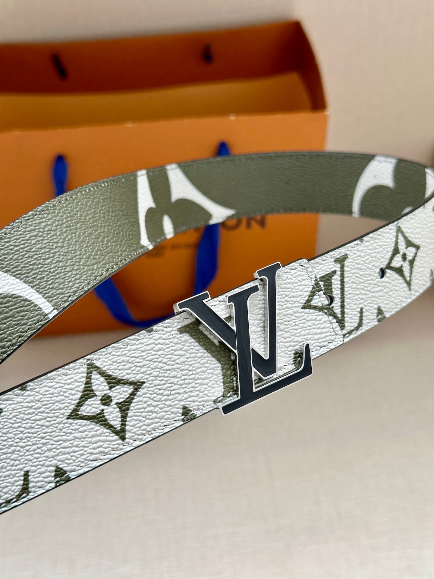 Louis Vuitton belt close-up: white monogram strap, dark green edge, silver LV buckle