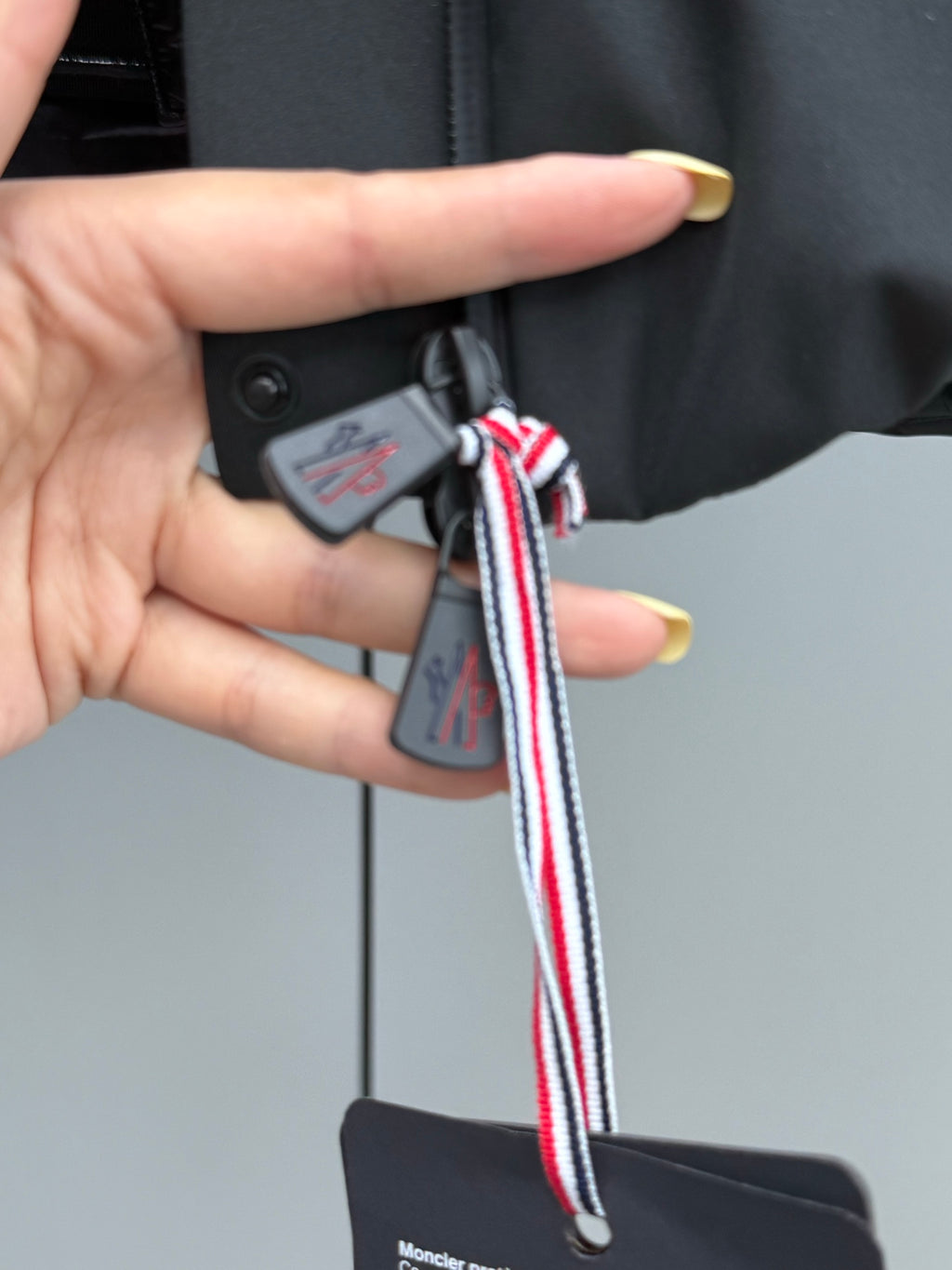 Black puffer jacket hood tag with red, white, and blue lanyard