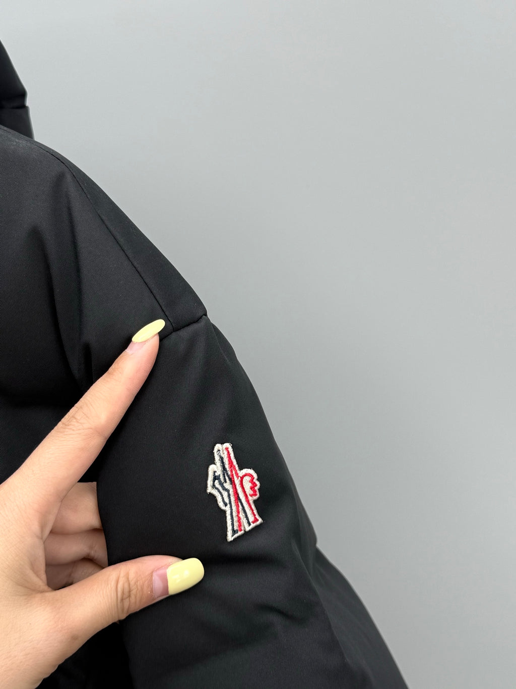 Black puffer jacket sleeve with small logo patch