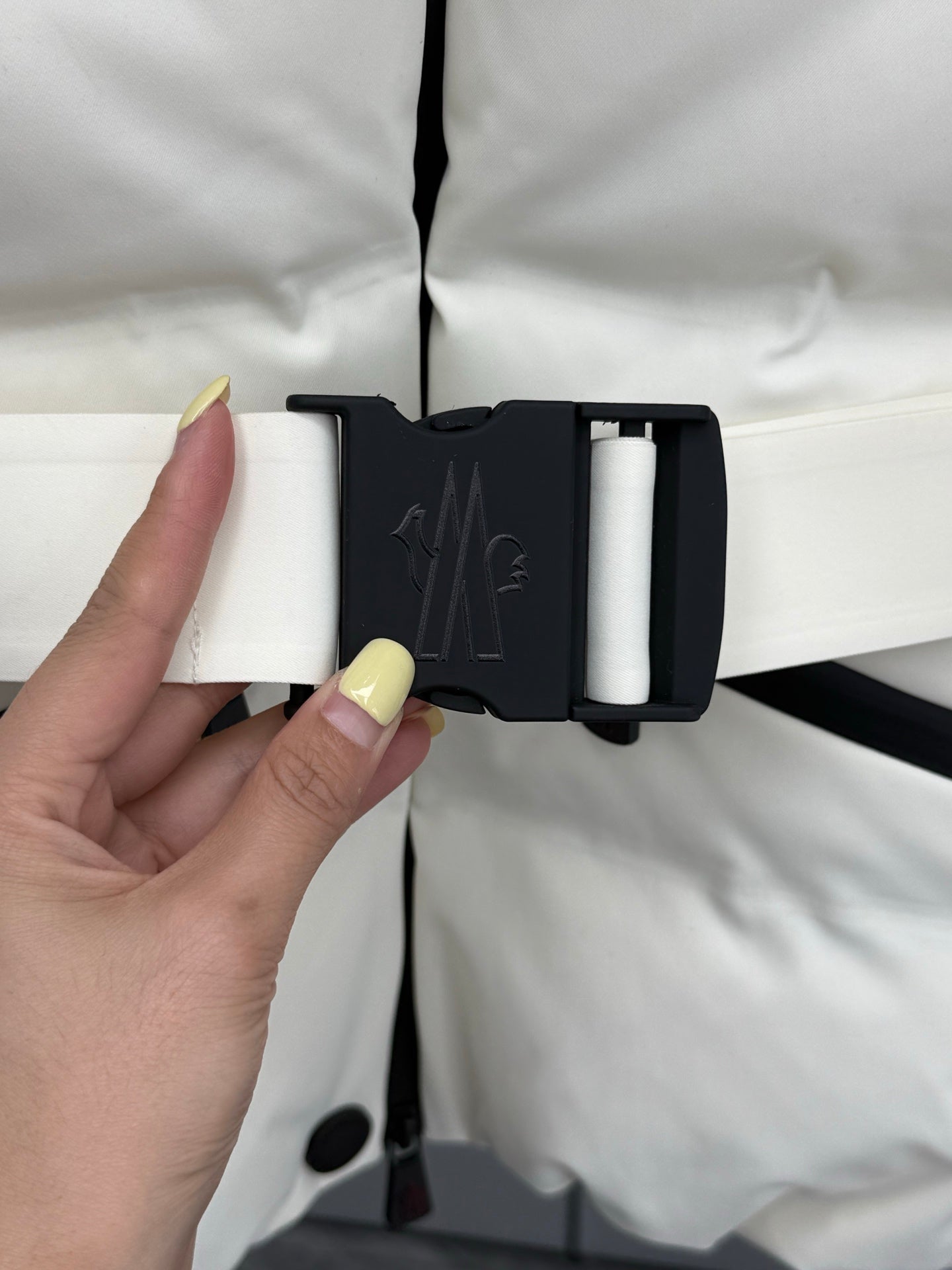 White puffer jacket with hood toggle-style belt and snap buttons, close-up