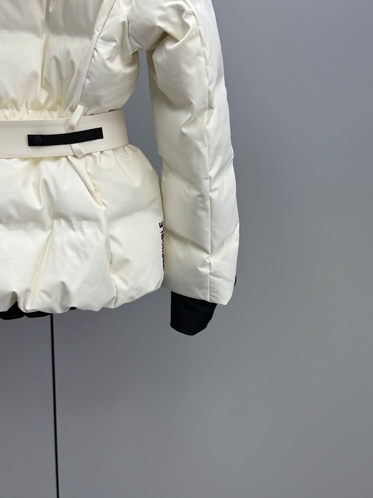 White puffer jacket with wide black belt and long sleeves, side view