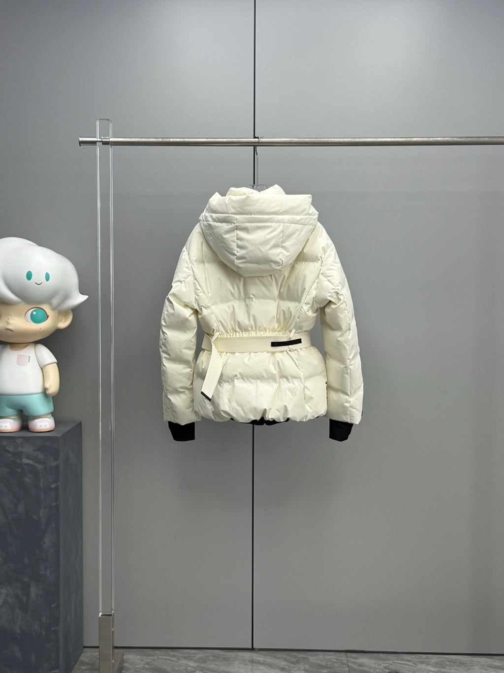 White long puffer jacket with hood and black cuffs, front view on hanger