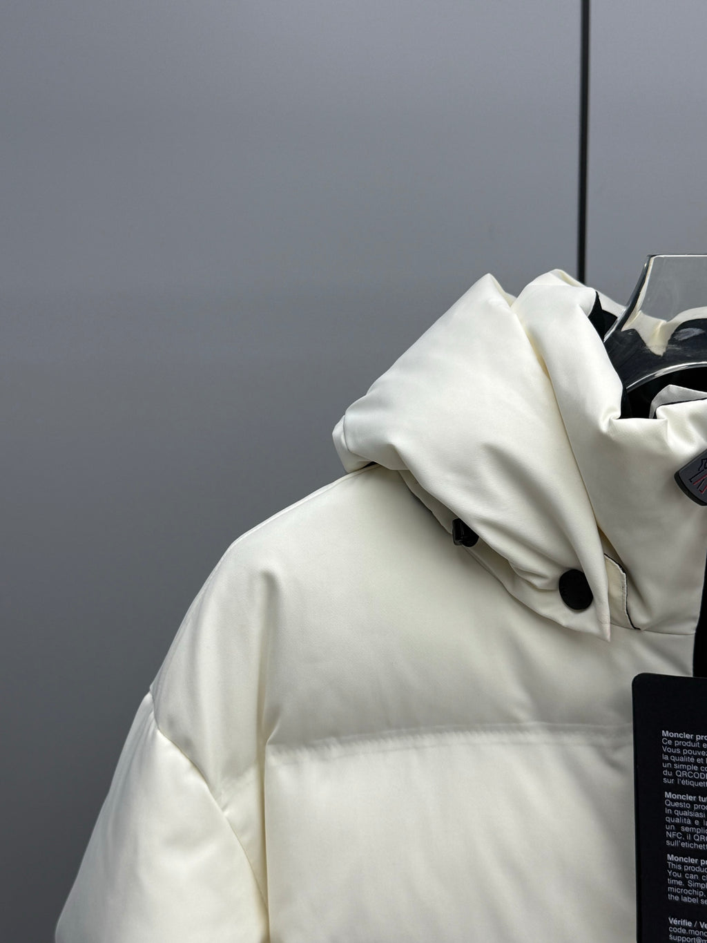 White hooded puffer jacket with front buttons and black trim near the zipper