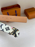 Leather belt with tan back and gold LV buckle, monogram strap visible