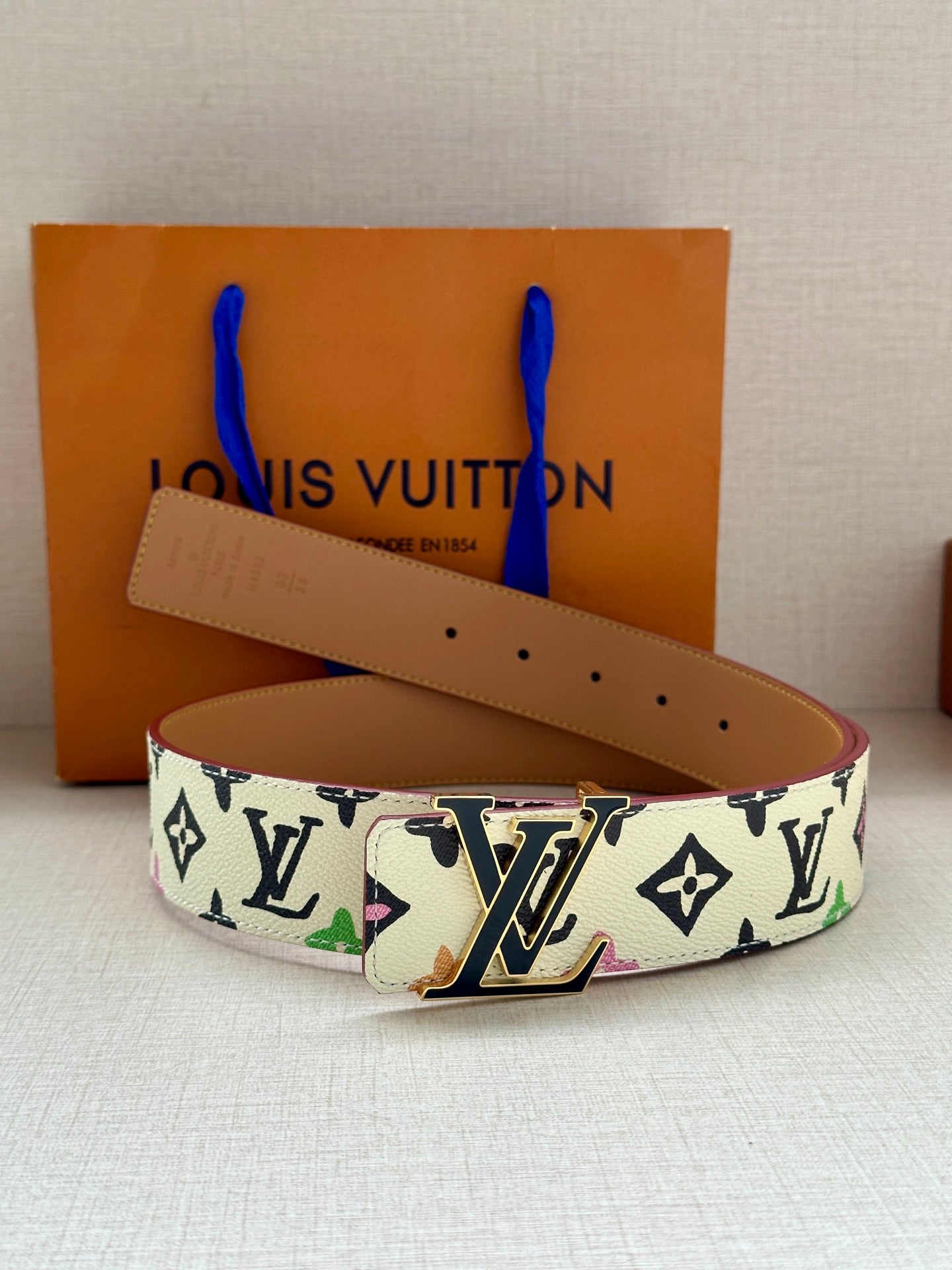 Leather LV monogram belt with tan strap and gold buckle, angled view