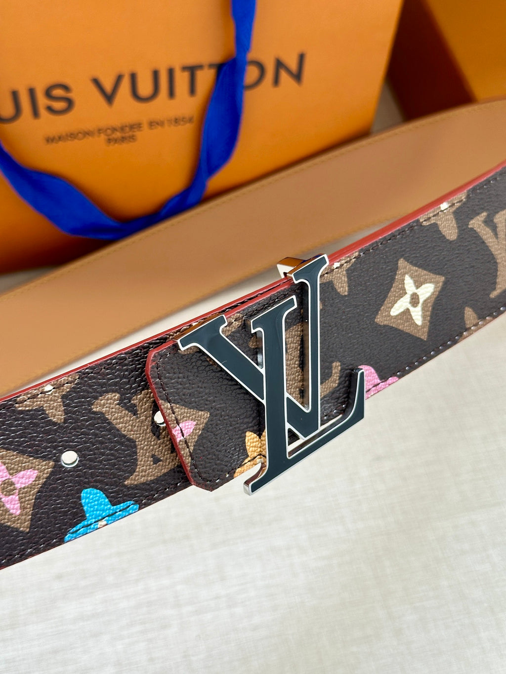 Navy monogram belt with silver LV buckle and tan lining, side close-up