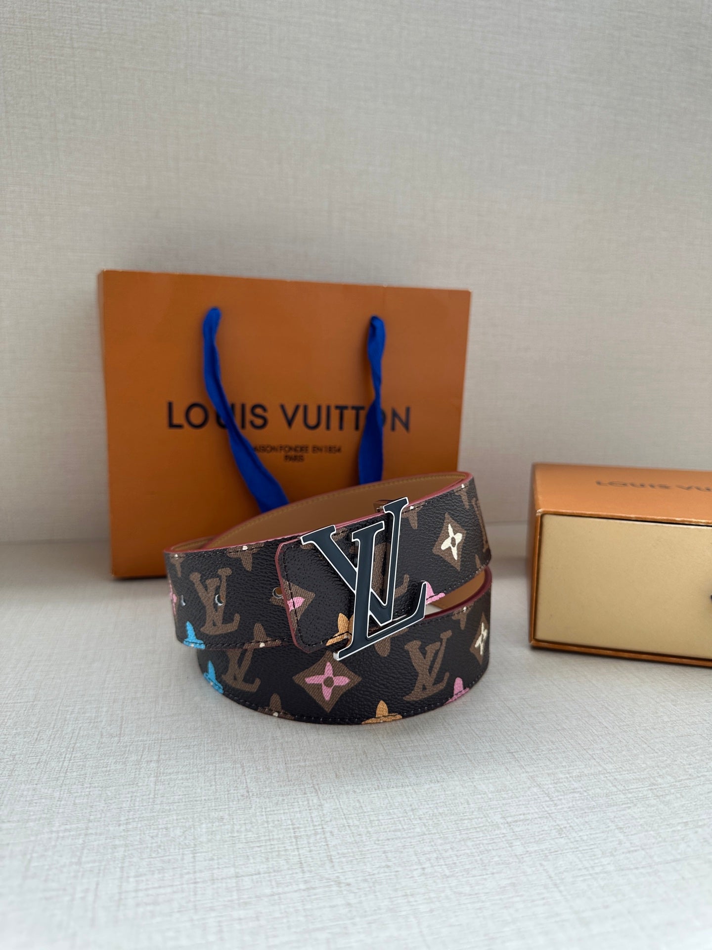Wide designer belt with navy monogram canvas, multicolor motifs, silver buckle