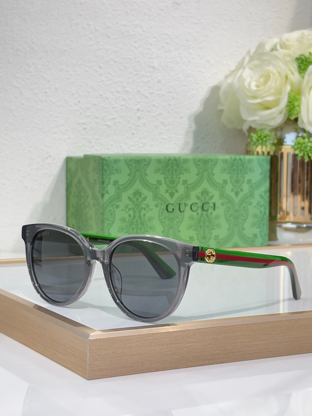 Gucci round sunglasses with black frames, multicolor temple stripes, gold hinge detail.