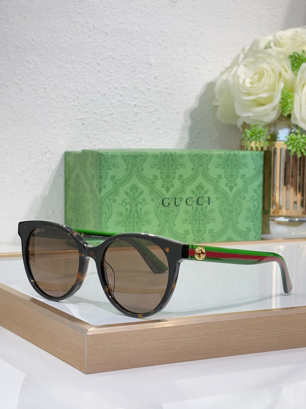 Gucci round sunglasses with black frames, multicolor temple accents, gold logo centerpiece.