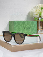 Gucci round sunglasses with black frames, multicolor temple accents, gold logo centerpiece.