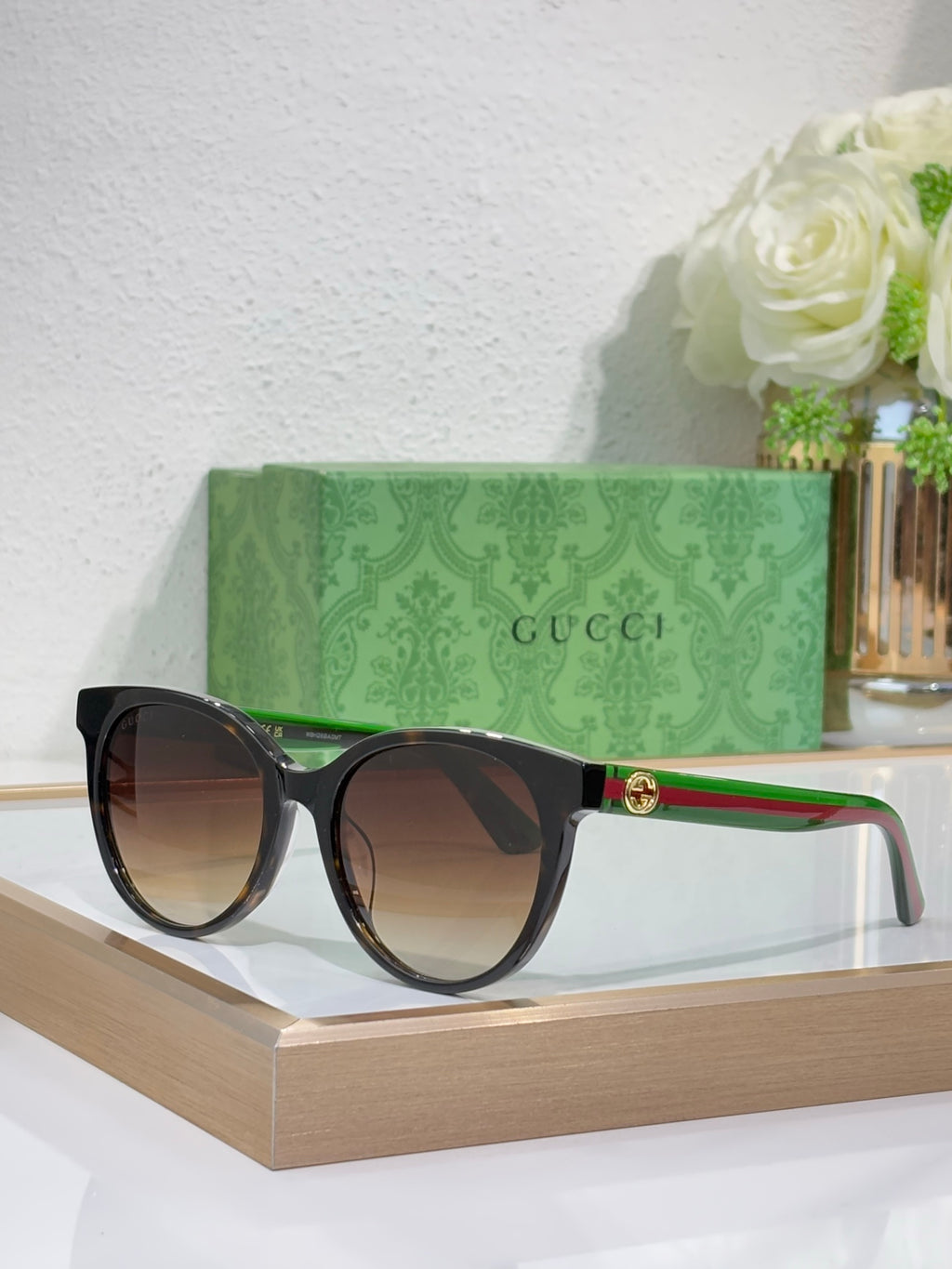 Gucci black round sunglasses with dark lenses, green/red temple stripe and gold emblem.