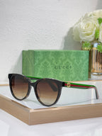 Gucci black round sunglasses with dark lenses, green/red temple stripe and gold emblem.