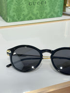 Gucci round sunglasses with dark lenses and glossy black full-rim frame