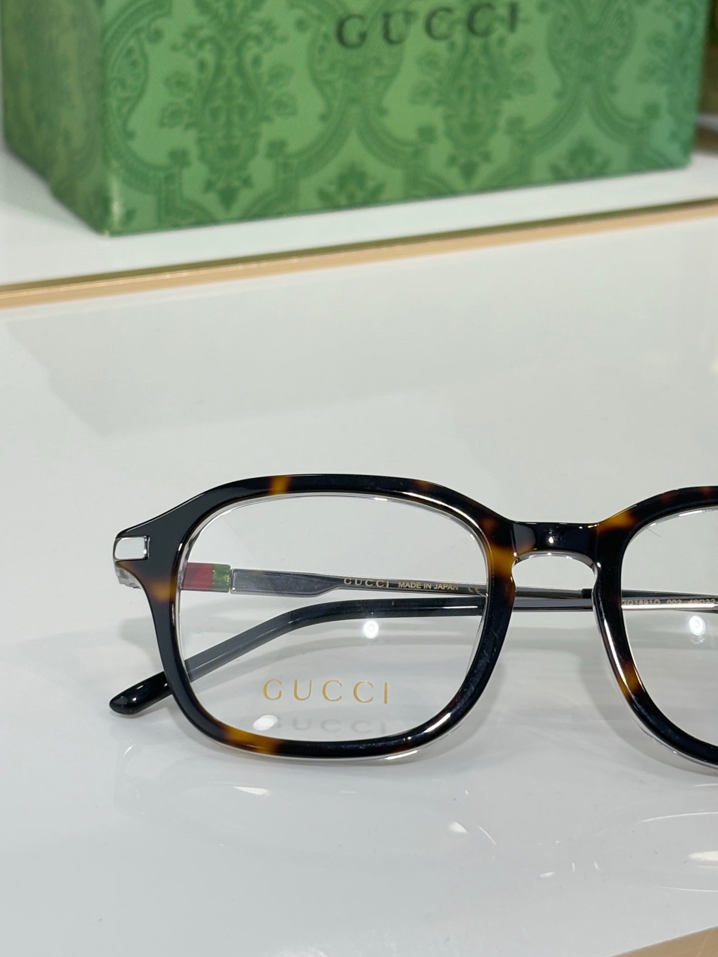 Gucci eyeglasses close-up with dark oval frames and tortoise-accent temples