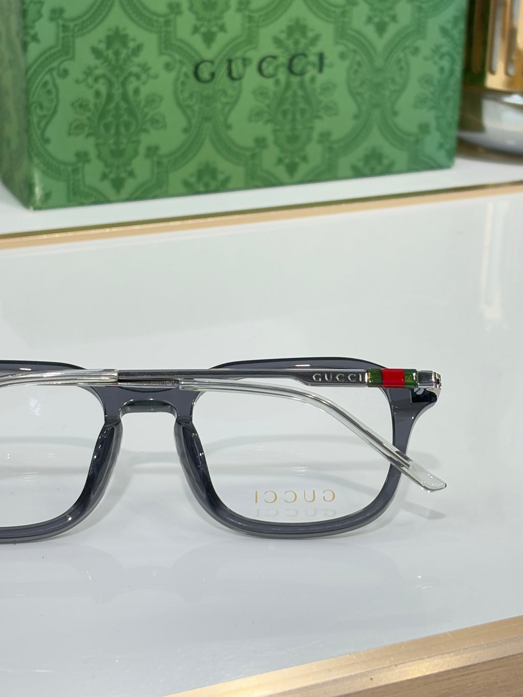 Gucci eyeglasses side view with dark frame and temple stripe, clear lenses