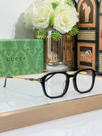 Gucci eyeglasses with dark frames and clear lenses, gold-tone temple with stripe