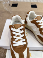 Dior unisex sneakers close-up, brown suede with white panels and lace eyelets.