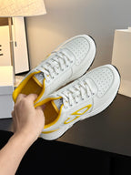 White low-top sneakers with yellow interior and side emblem, viewed from side