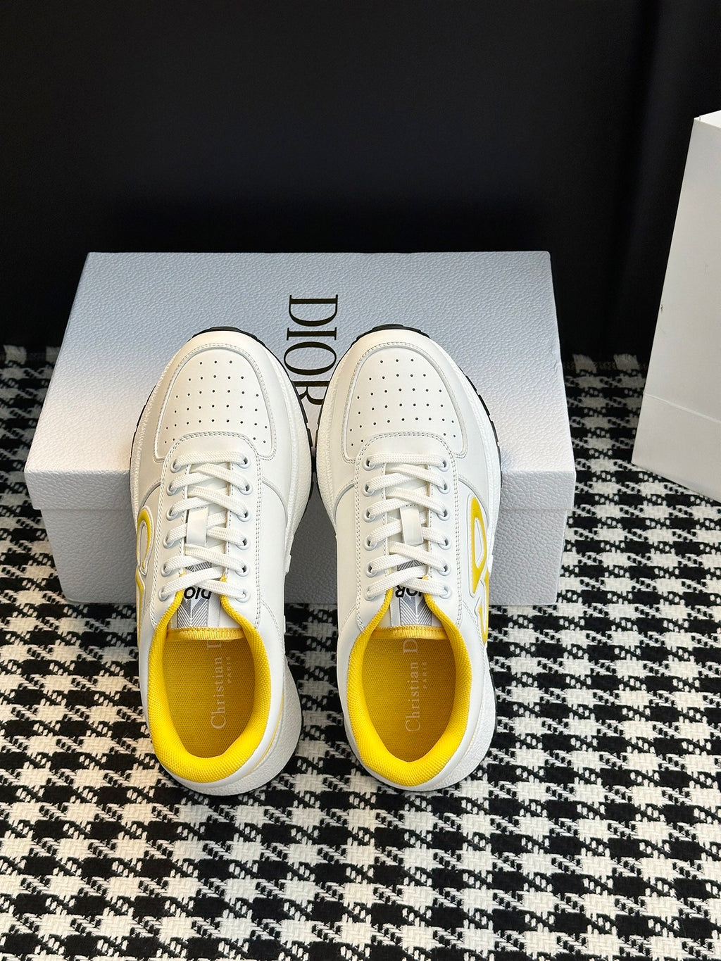 White low-top sneakers with perforated uppers, white laces, and yellow interior lining