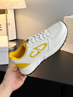White low-top sneakers with yellow interior, lace-up front, and side emblem
