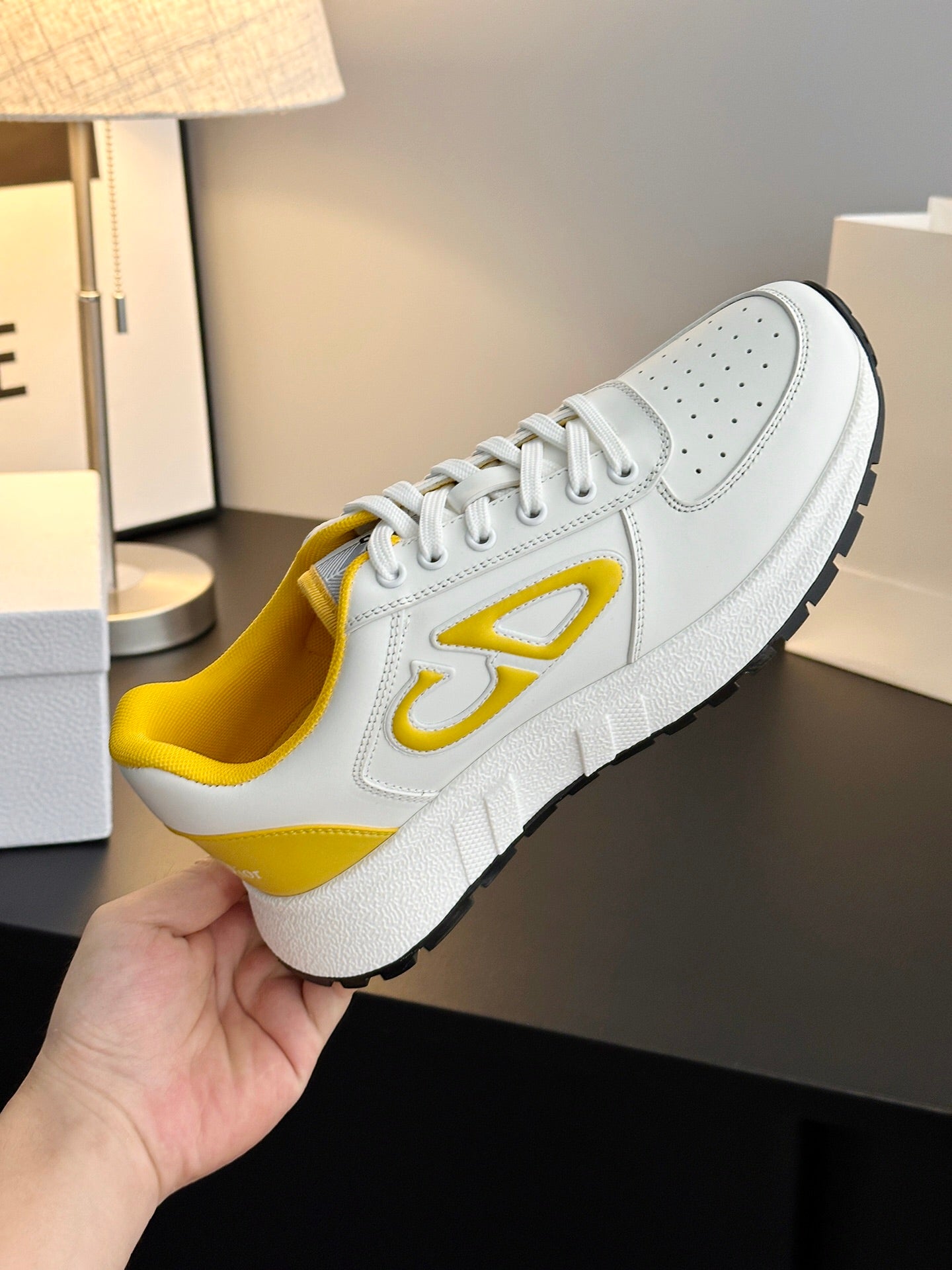 White low-top sneakers with yellow interior, lace-up front, and side emblem