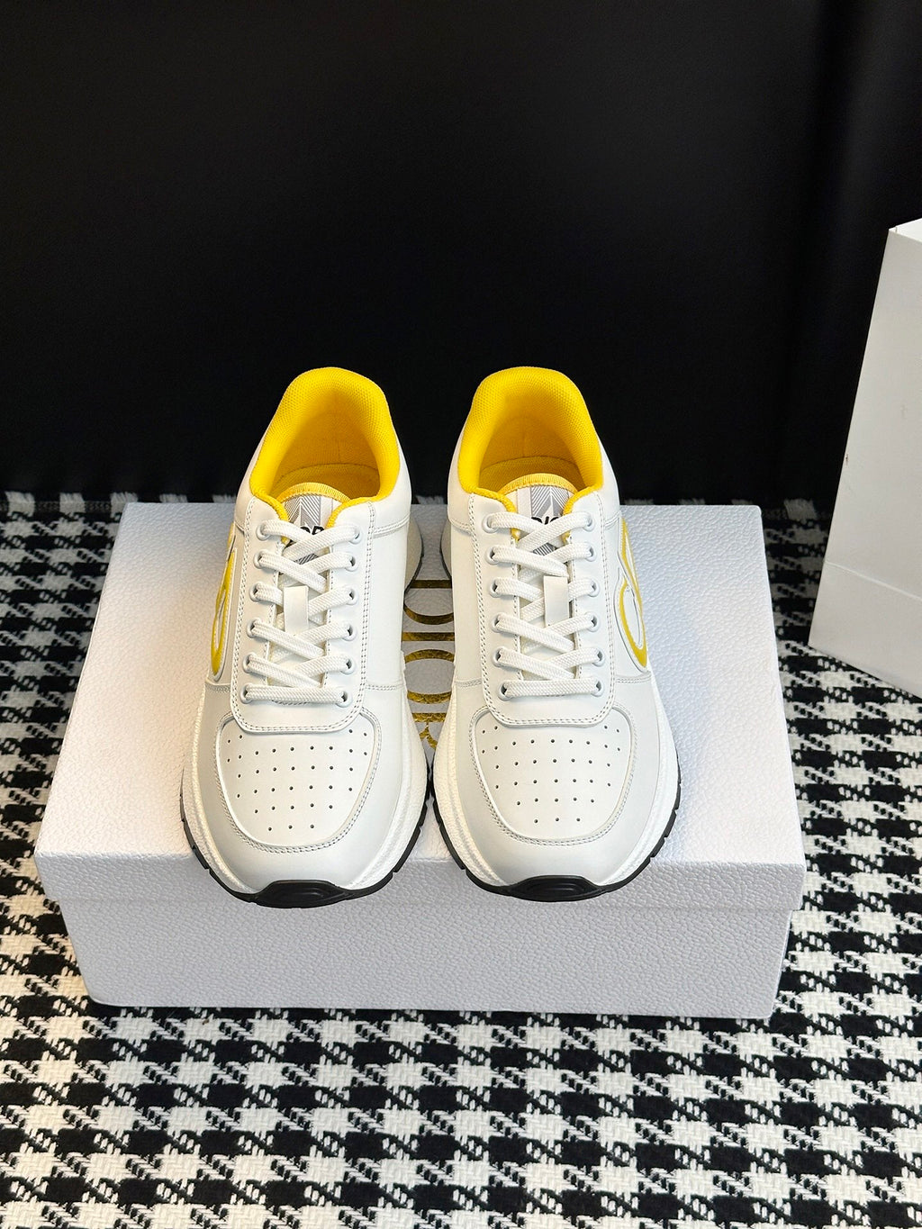 Pair of white low-top sneakers with yellow lining and white lace-up closure
