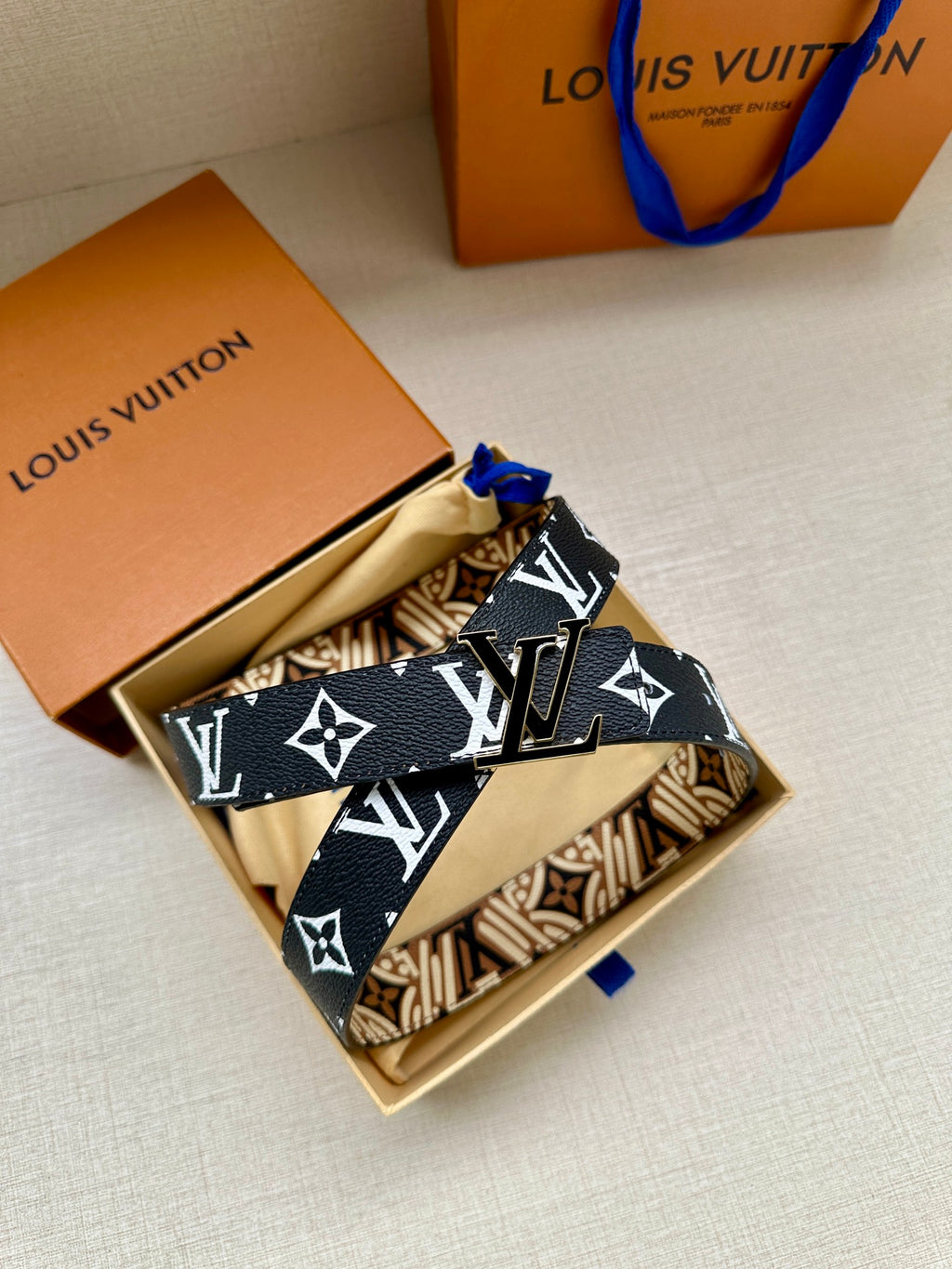 Louis Vuitton belt laid flat with dark blue strap and repeating white logo motifs