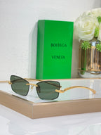 Sunglasses with dark green lenses and gold-tone hinges, side-front view