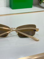 Sunglasses close-up with brown lenses and gold crossbar bridge