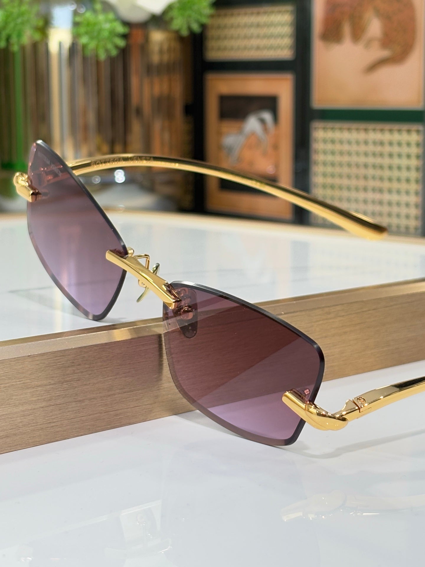 Sunglasses side view with mauve lenses and gold frame with hinge detail