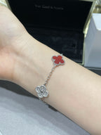 Silver-tone clover charm bracelet with red enamel on wrist