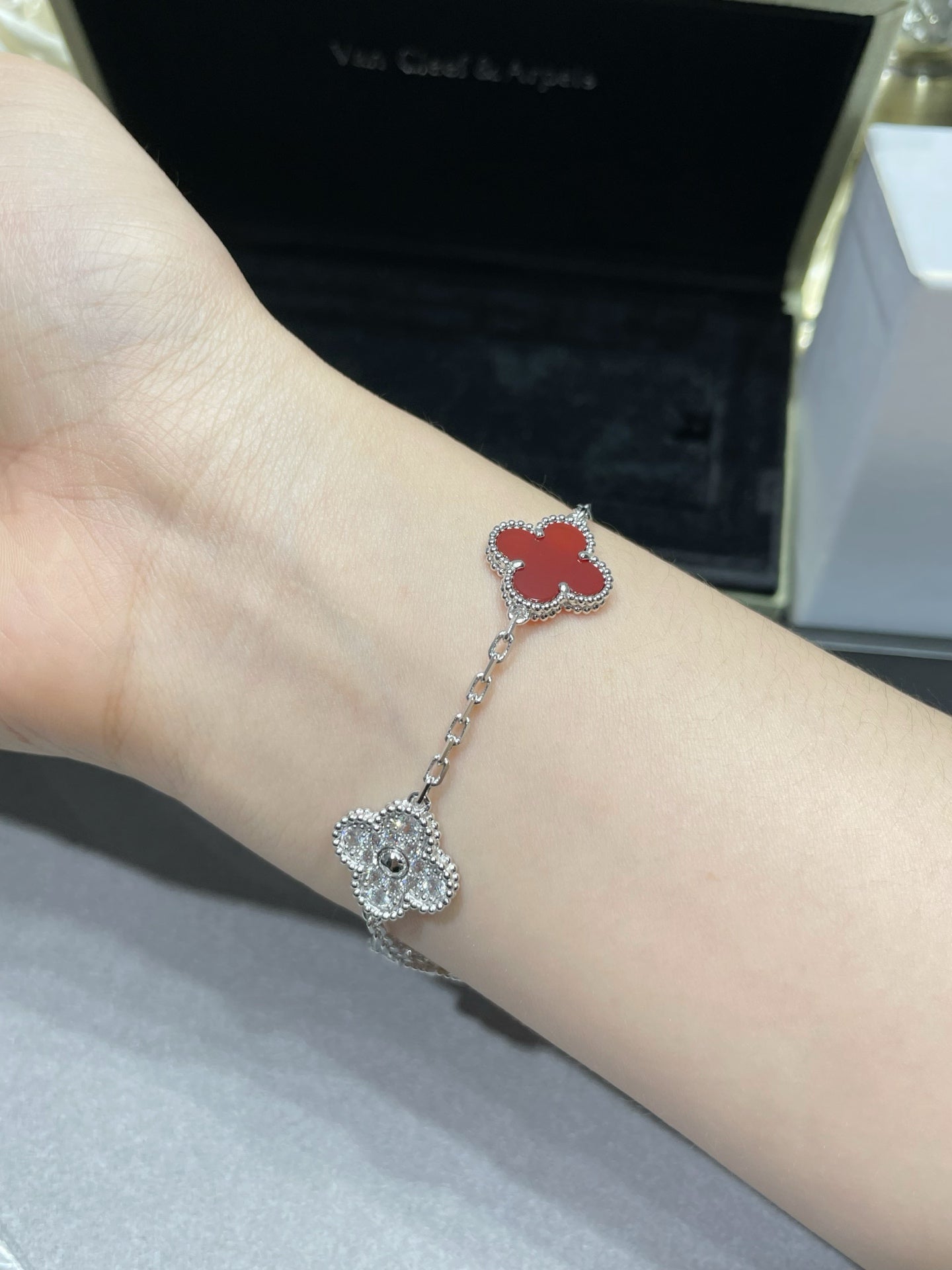 Silver-tone clover charm bracelet with red enamel on wrist