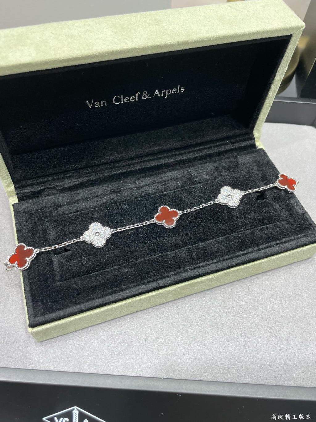Silver-tone clover bracelet with red enamel and pavé links on velvet tray
