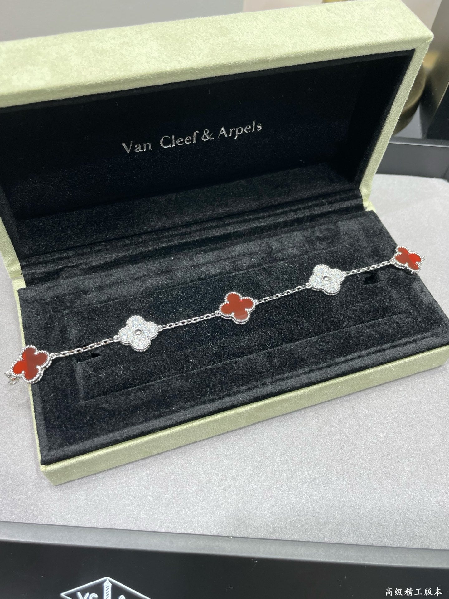 Silver-tone clover bracelet with red enamel and pavé links on velvet tray