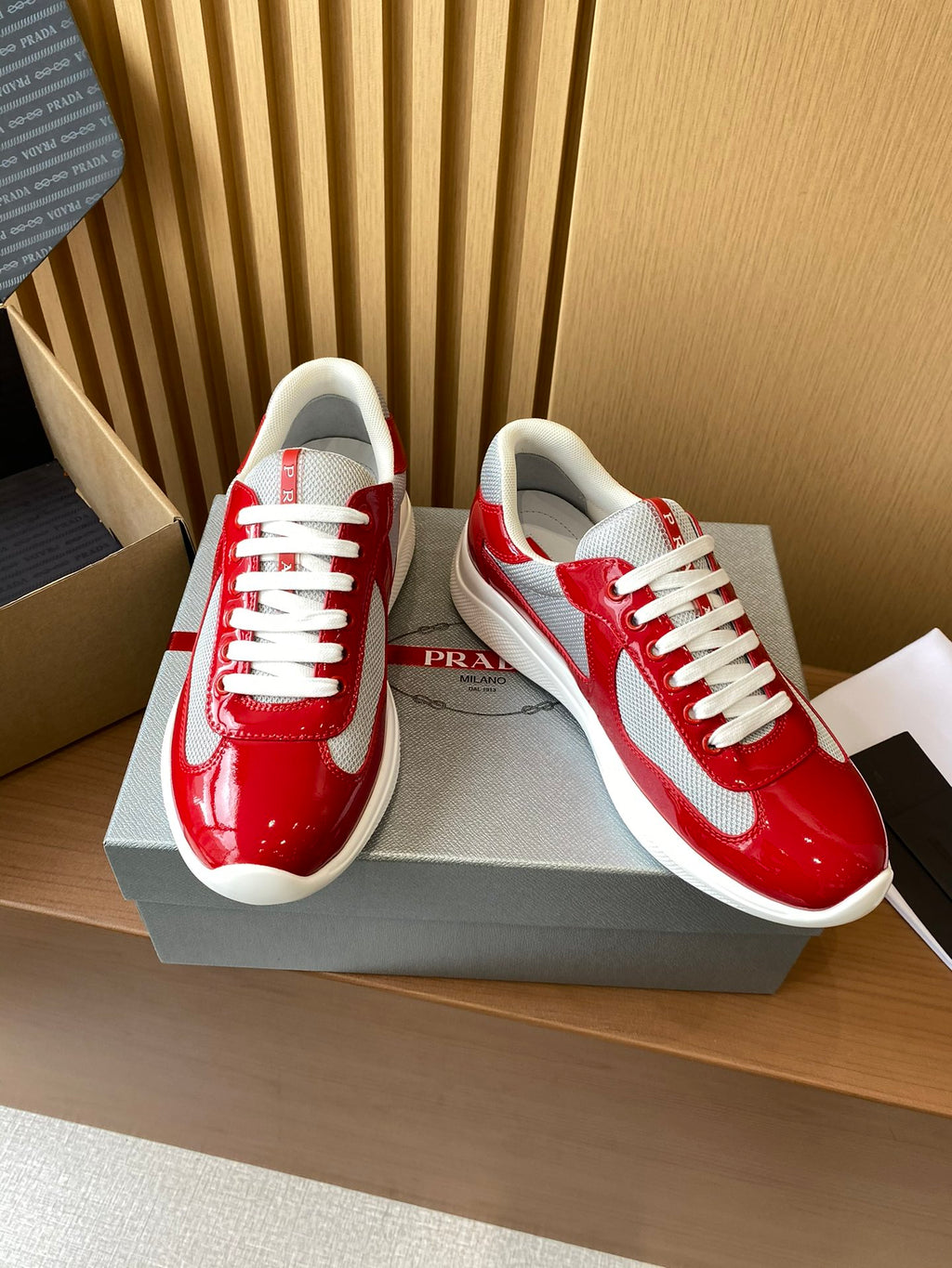 Prada unisex sneakers with red glossy upper, white side panel, and lace-up design