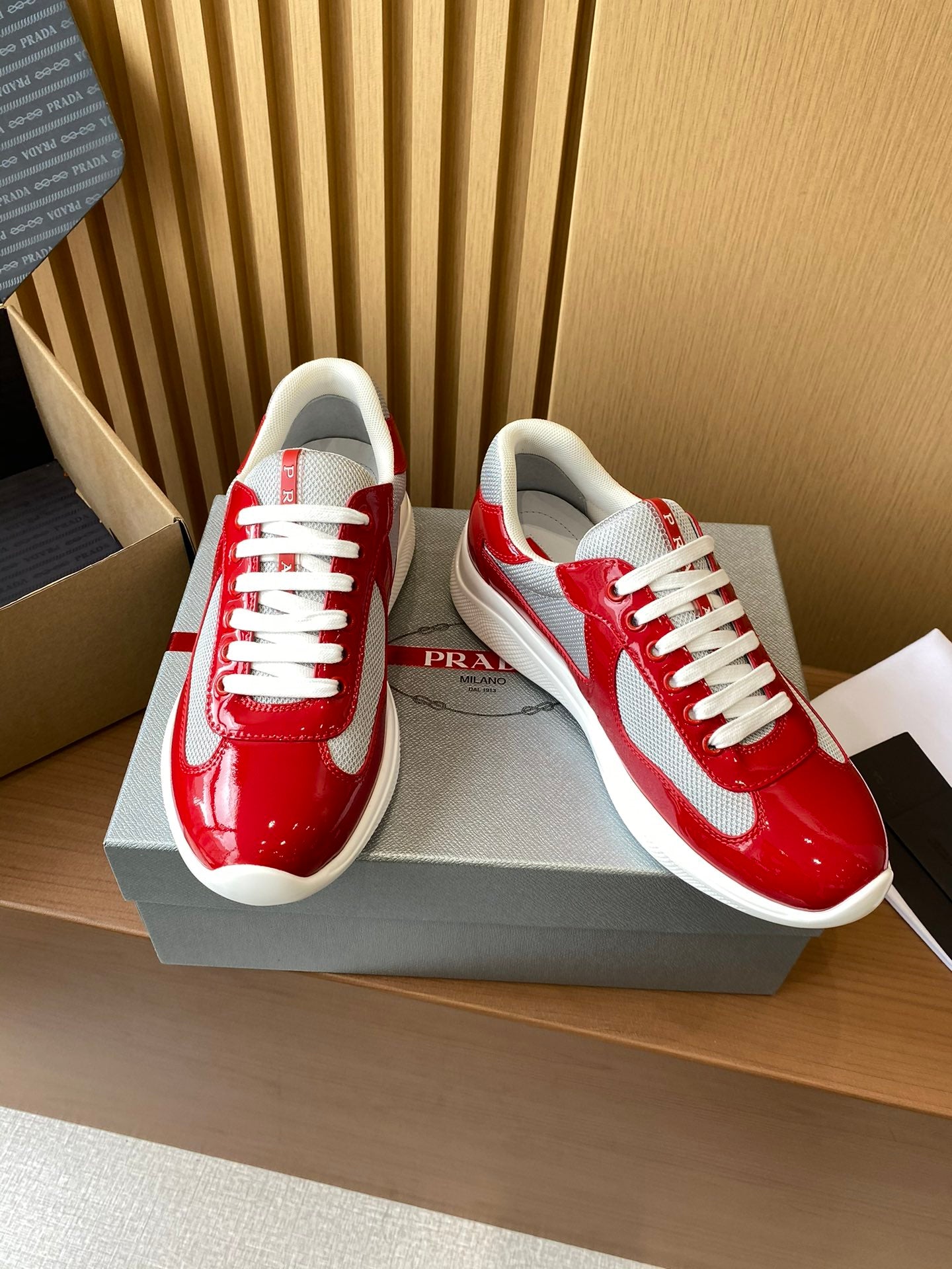 Prada unisex sneakers with red glossy upper, white side panel, and lace-up design