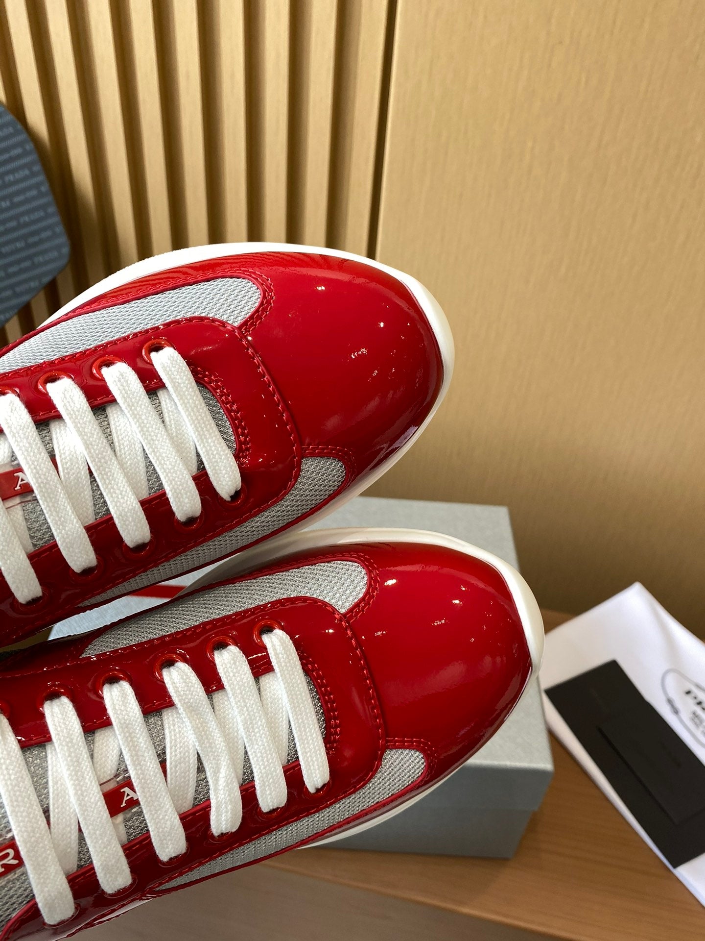 Prada unisex sneakers toe area in red patent with white laces and textured finish