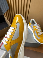 Prada unisex sneaker side view, glossy yellow leather with gray mesh paneling