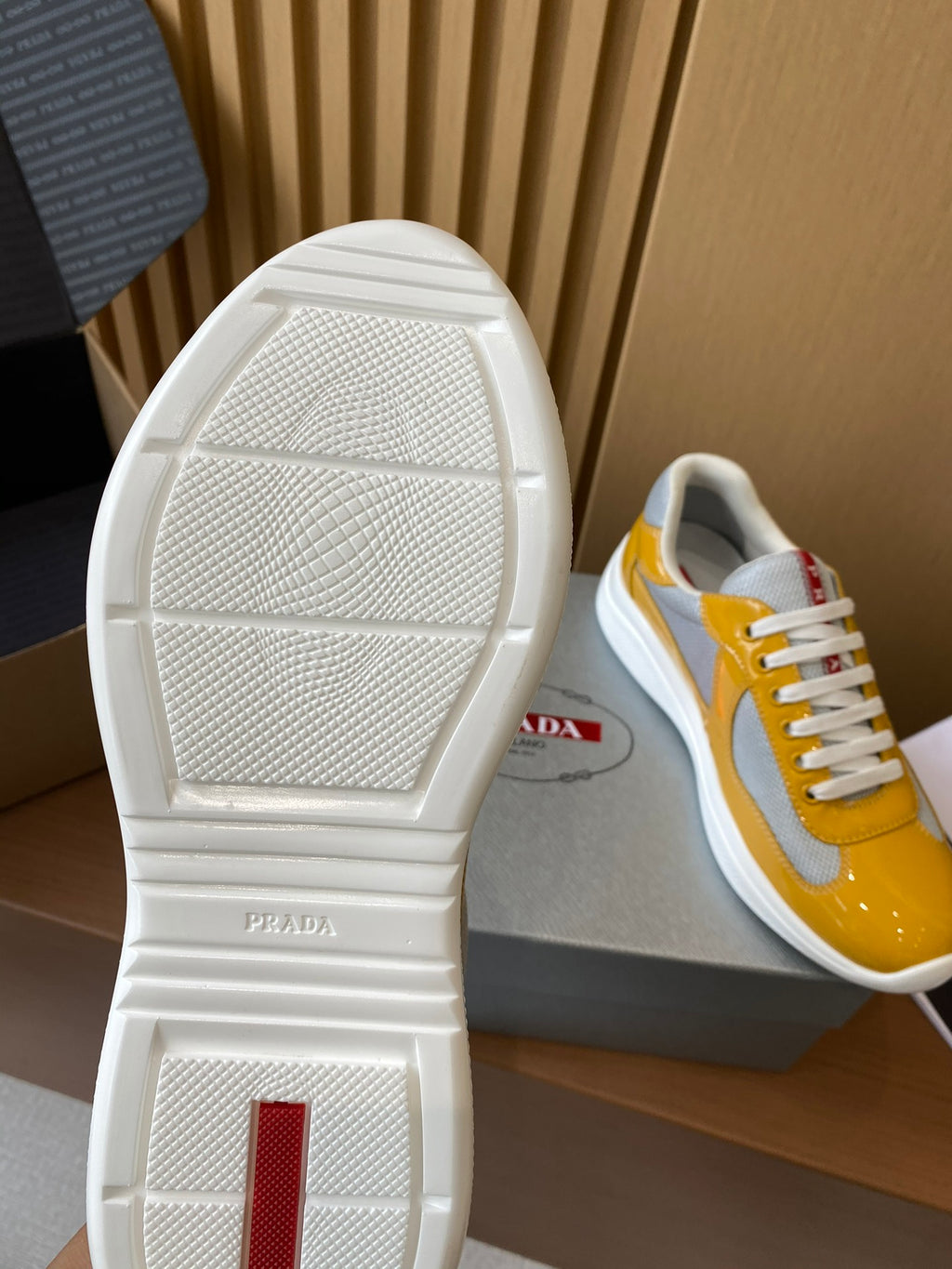 Prada unisex sneakers outsole view with white tread and yellow-and-gray upper