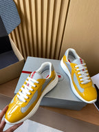 Prada unisex sneakers close-up, yellow patent toe with white laces and red tab