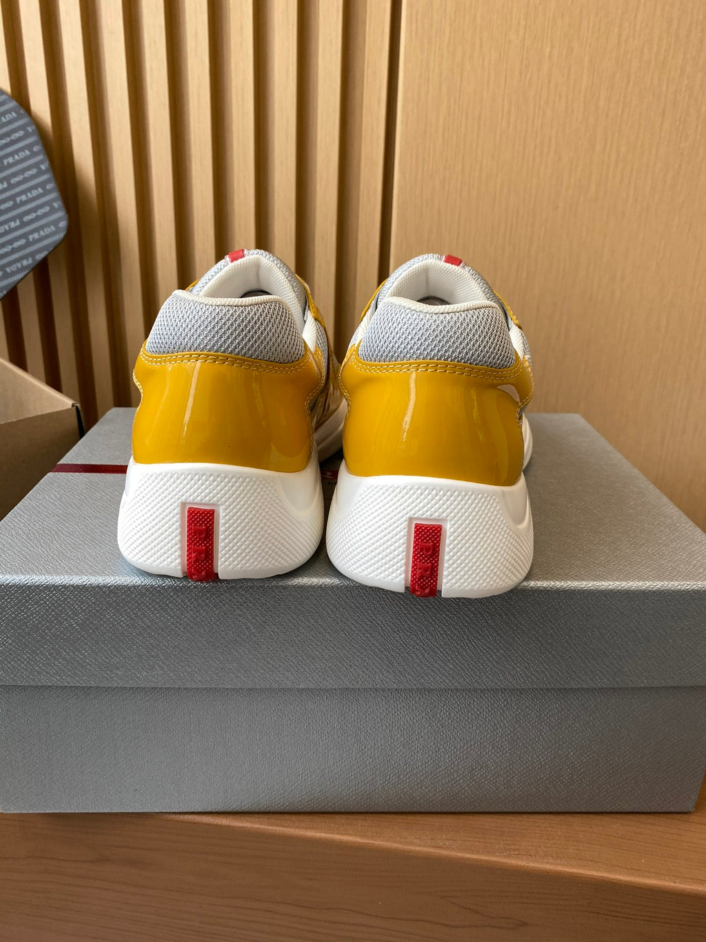 Prada unisex sneakers back view, yellow uppers with white heel tabs and red strip