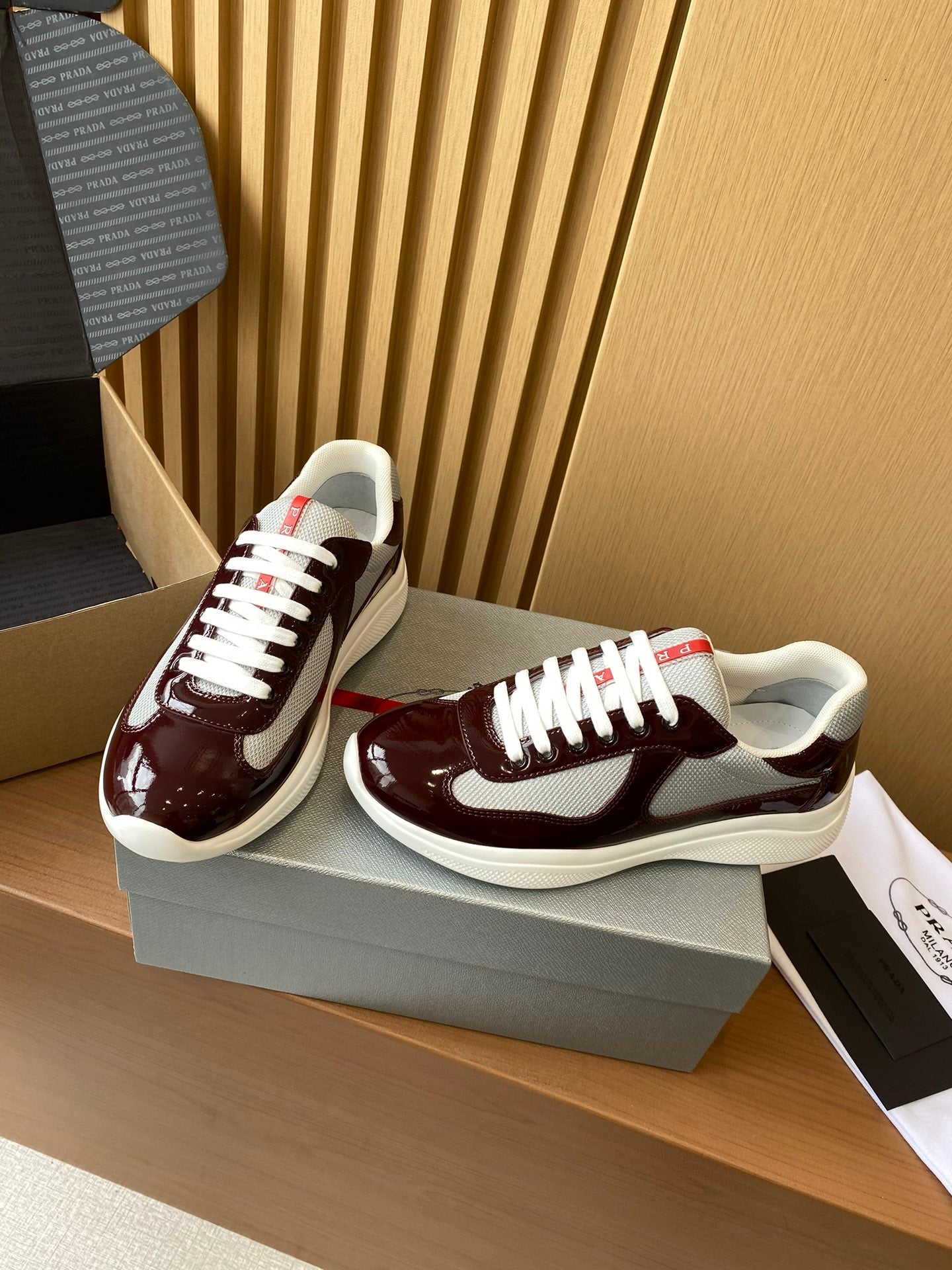 Burgundy and white low-top sneakers with textured upper and white laces, side profile