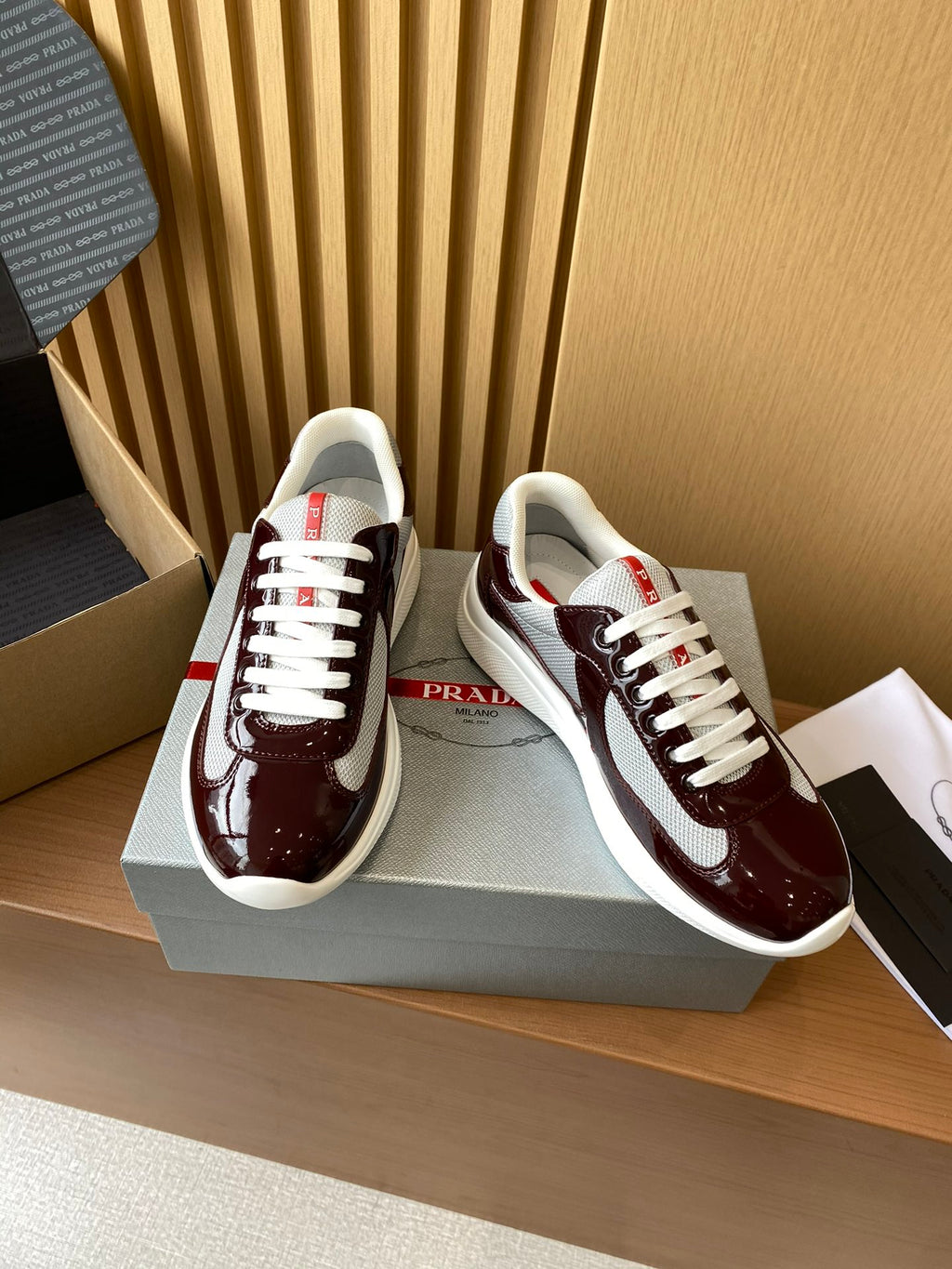 Burgundy low-top sneakers with white laces and white sole, side logo patch visible